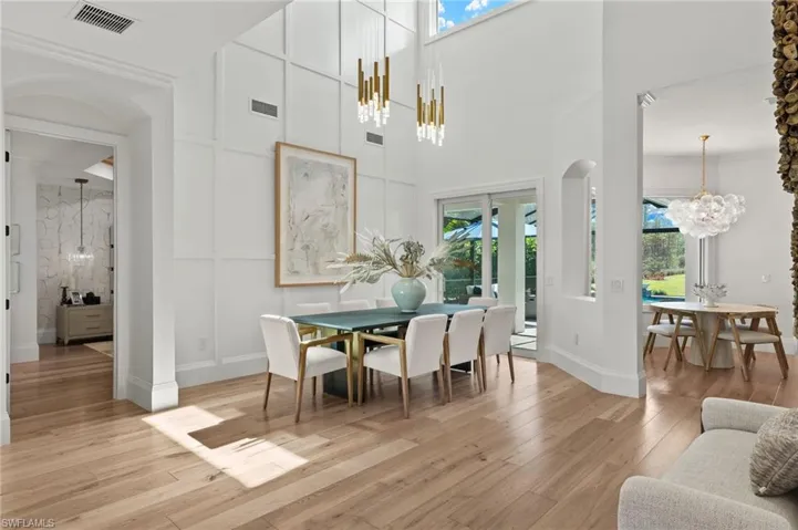 Dining room with light hardwood / wood-style flooring, a notable chandelier, a towering ceiling, and plenty of natural light