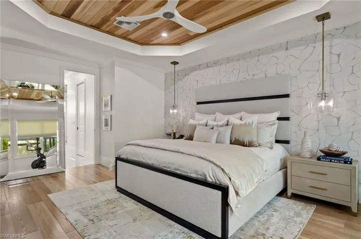 Bedroom with wood ceiling, ceiling fan, a raised ceiling, light hardwood / wood-style flooring, and crown molding