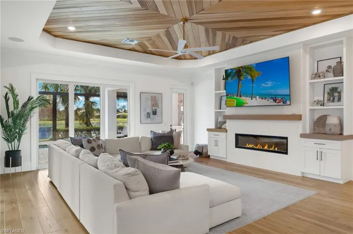 Living room with light hardwood / wood-style flooring, wood ceiling, a tray ceiling, and built in features