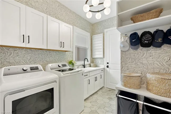 Washroom with light tile patterned flooring, cabinets, sink, and washing machine and clothes dryer