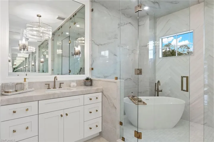 Bathroom with tile patterned flooring, separate shower and tub, vanity, tile walls, and a chandelier