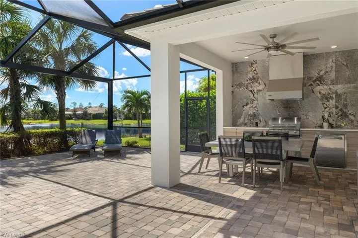 View of patio / terrace featuring area for grilling, a lanai, ceiling fan, a water view, and a grill