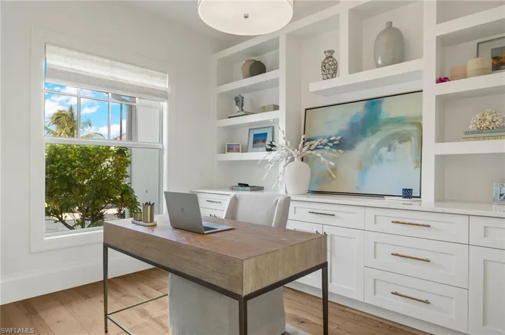 Office space with a healthy amount of sunlight, built in features, and light hardwood / wood-style flooring