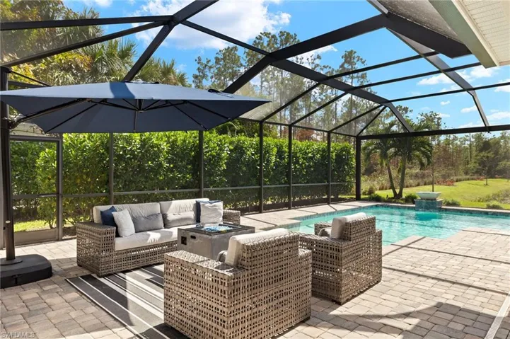 View of pool with an outdoor living space, a patio, and glass enclosure
