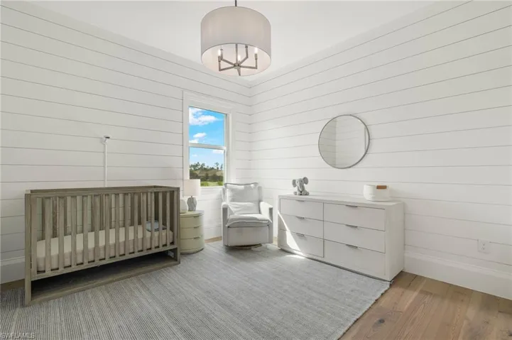 Bedroom with wood-type flooring, wooden walls, and a nursery area