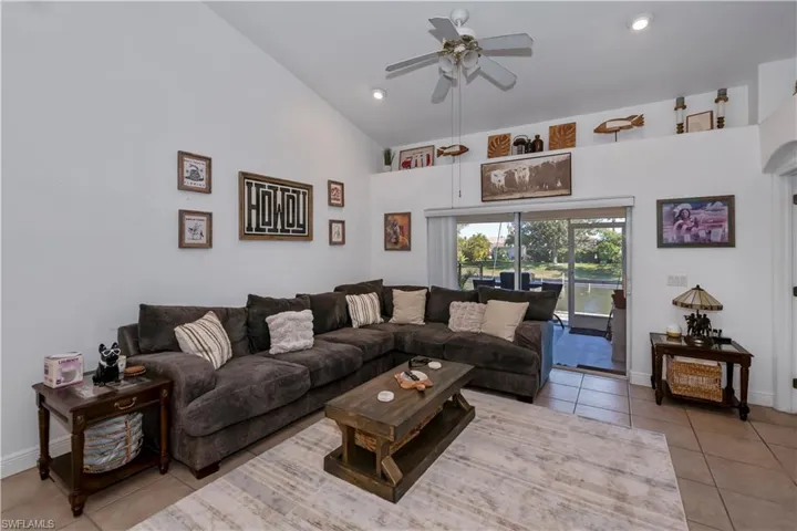 Living room featuring light tile patterned flooring, a ceiling fan, high vaulted ceiling, recessed lighting, and baseboards