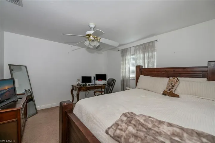 Bedroom with carpet floors, a desk, baseboards, and ceiling fan