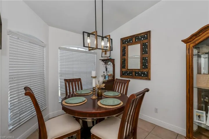 Dining space featuring vaulted ceiling, light tile patterned floors, and baseboards