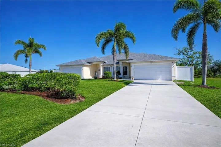 Ranch-style home with a front lawn, an attached garage, driveway, and stucco siding