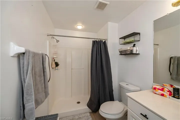 Full bathroom with toilet, curtained shower, and vanity