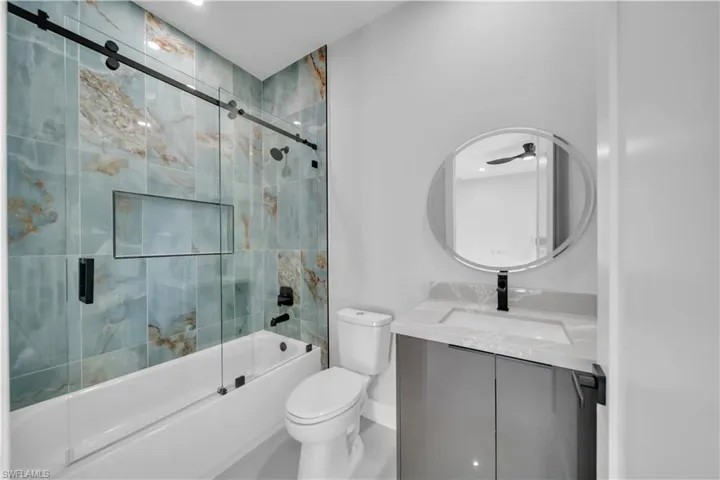 Bathroom with combined bath / shower with glass door and vanity