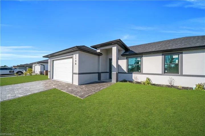 Prairie-style house featuring a front yard, stucco siding, decorative driveway, and an attached garage