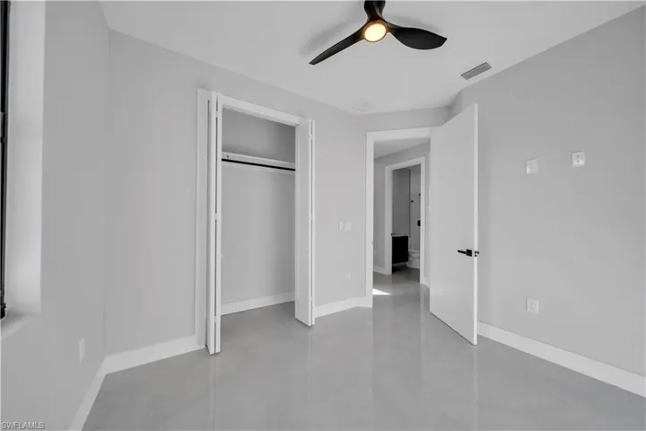 Unfurnished bedroom featuring ceiling fan, a closet, and concrete floors
