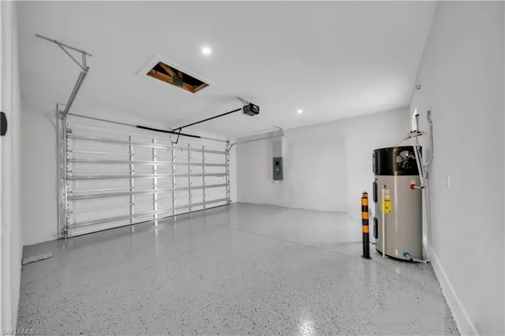 Garage with water heater, electric panel, and recessed lighting