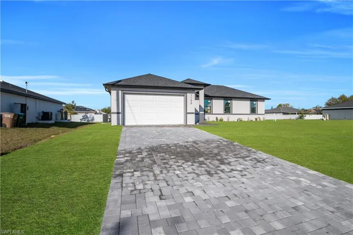 View of front of house featuring a front lawn, decorative driveway, a shingled roof, a garage, and stucco siding