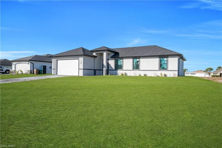 Prairie-style home with a front lawn, stucco siding, concrete driveway, and a garage
