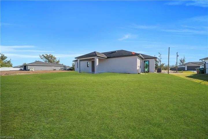 View of side of property featuring a lawn and stucco siding