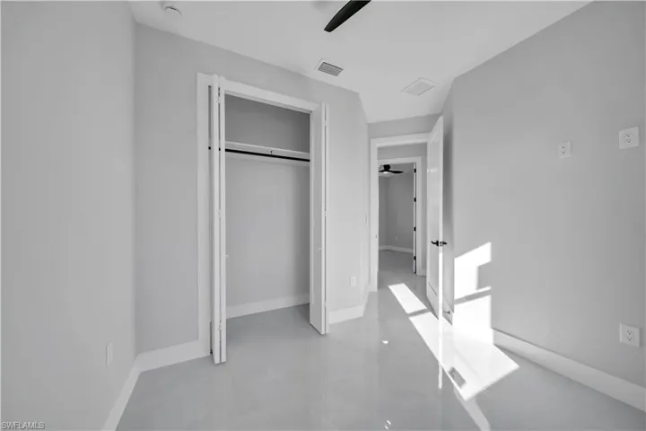 Unfurnished bedroom with finished concrete flooring, a closet, and a ceiling fan