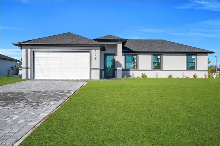 Prairie-style home with a front lawn, stucco siding, roof with shingles, and decorative driveway