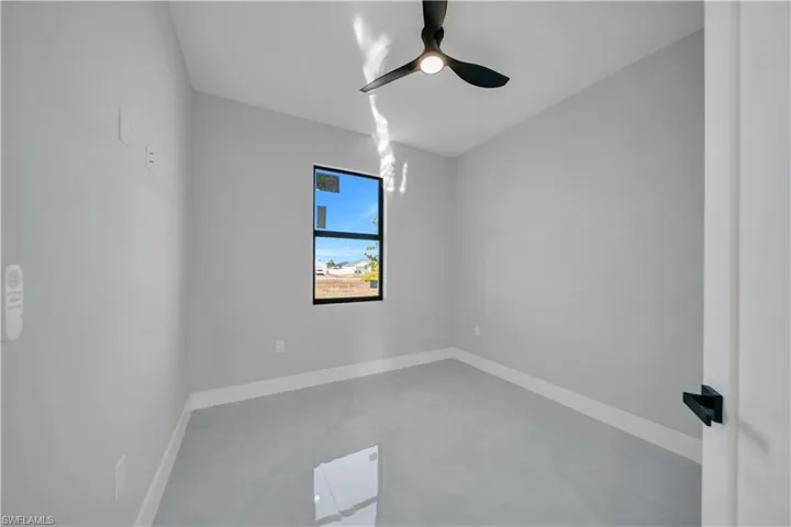 Unfurnished room featuring finished concrete flooring and ceiling fan