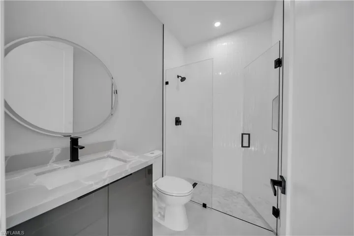 Bathroom with a stall shower, vanity, and recessed lighting