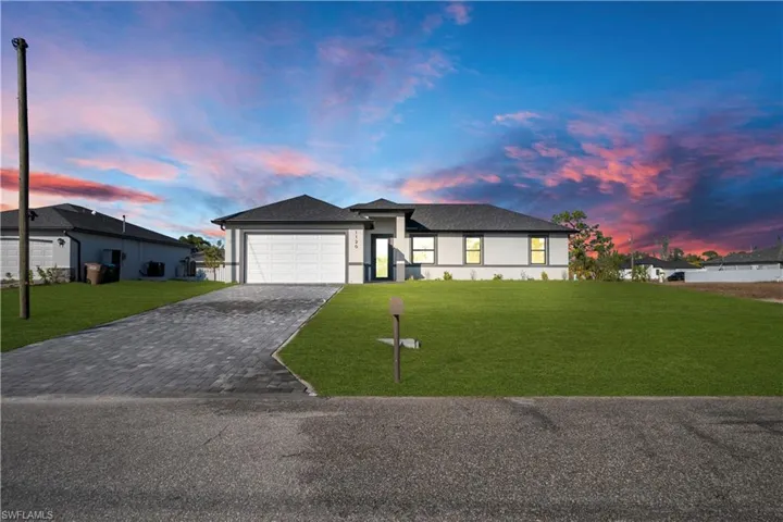 Prairie-style home with a front lawn, decorative driveway, an attached garage, and stucco siding