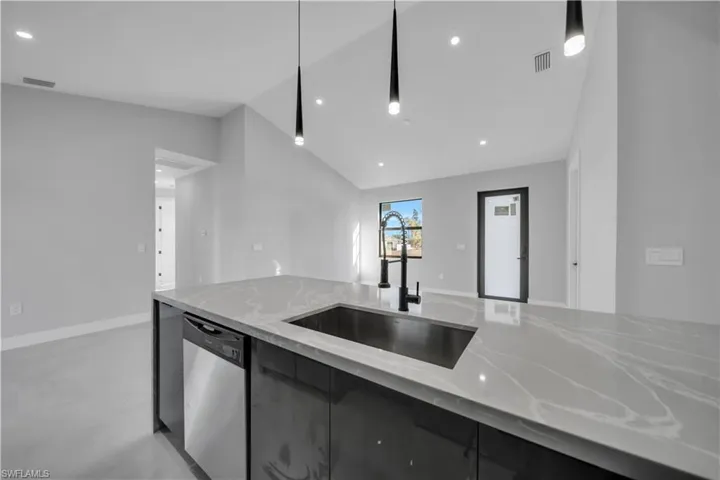 Kitchen with pendant lighting, finished concrete flooring, light stone countertops, dishwasher, and dark cabinets