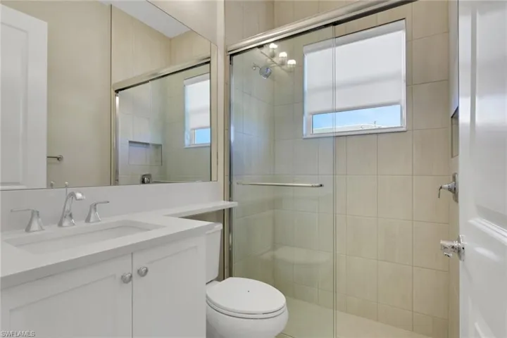 Bathroom featuring vanity and a walk in shower stall with natural lighting