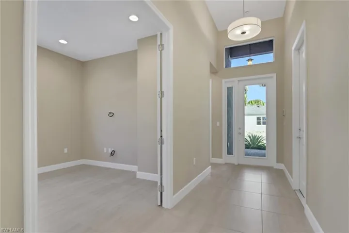 Foyer entrance with light tile patterned flooring and recessed lighting