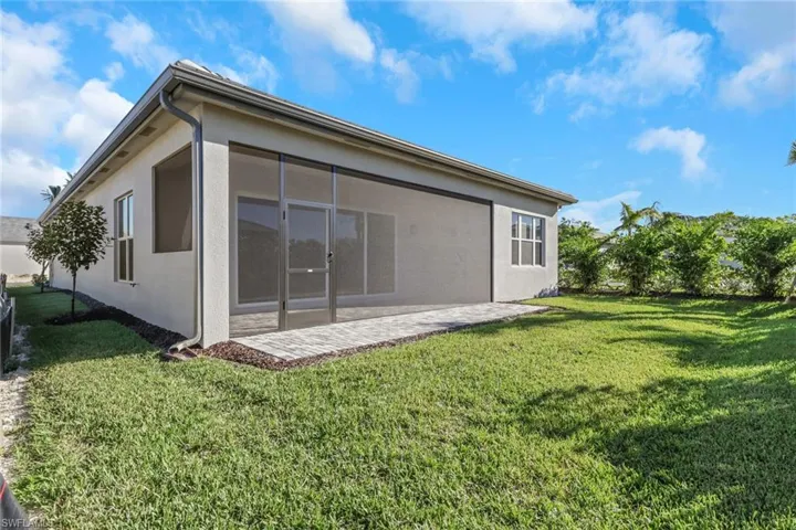 Back of property featuring stucco siding, a lawn, a sunroom, and a patio area