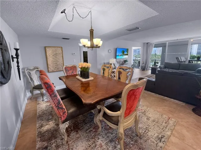 Dining area with a textured ceiling, a chandelier, and light tile patterned floors