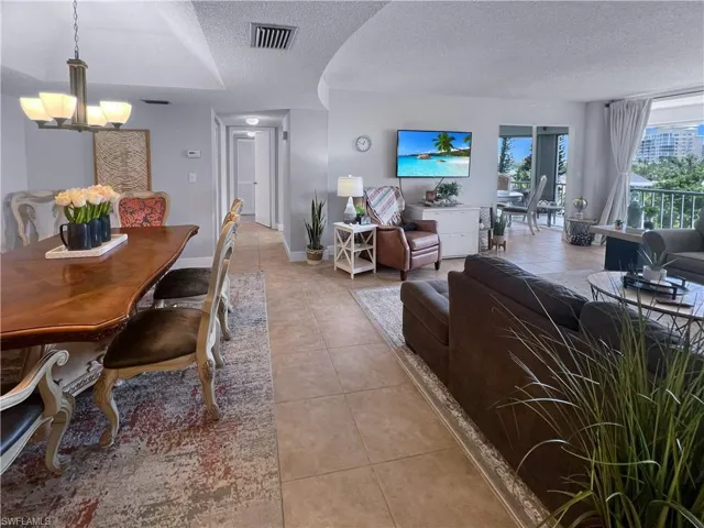 Dining area with a textured ceiling, light tile patterned floors, and a chandelier
