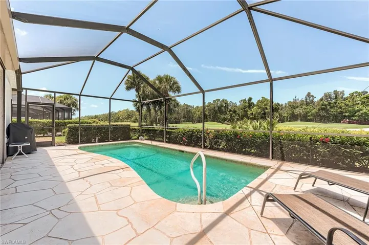 Outdoor pool with a patio, area for grilling, view of wooded area, and glass enclosure