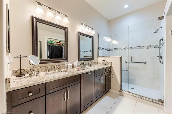 Bathroom featuring a shower stall, tile patterned floors, and double vanity