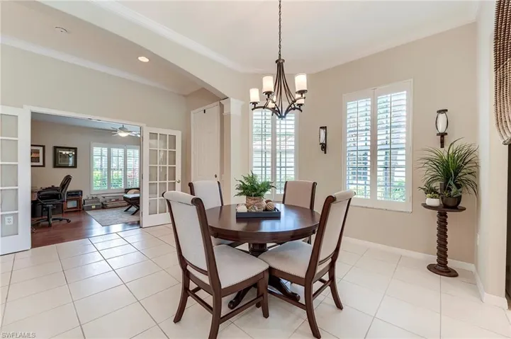 Dining room with a chandelier, an office area, light tile patterned floors, arched walkways, and french doors