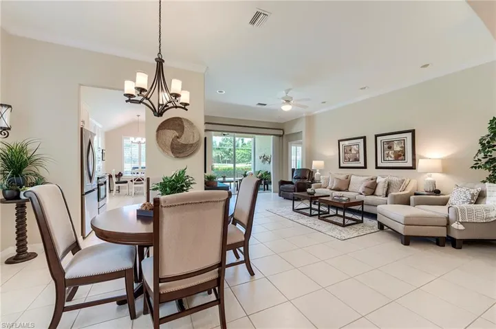 Dining area featuring crown molding, ceiling fan, a chandelier, light tile patterned flooring, and baseboards