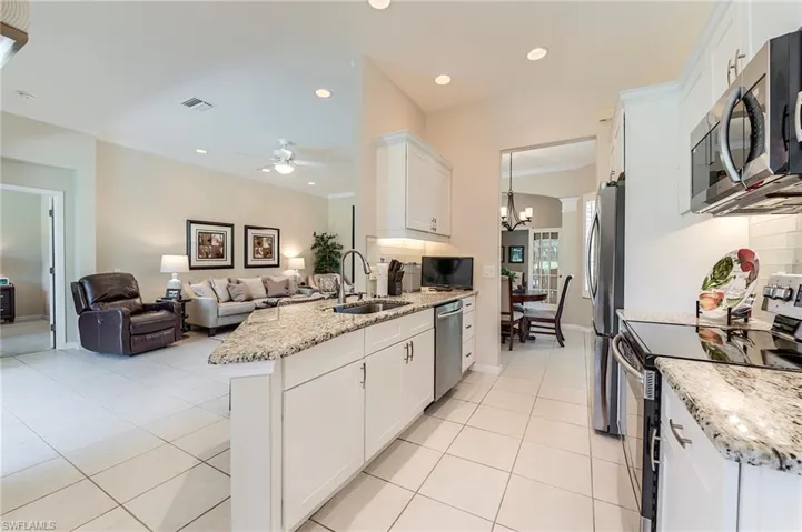 Kitchen featuring appliances with stainless steel finishes, a sink, white cabinetry, a ceiling fan, and light tile patterned flooring