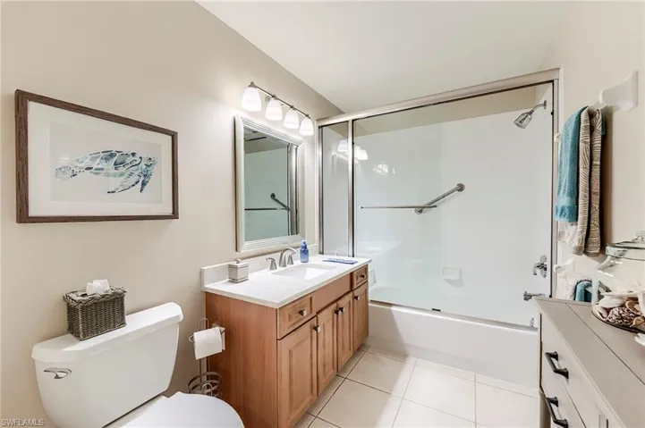 Full bath with toilet, vanity, tile patterned flooring, and bath / shower combo with glass door