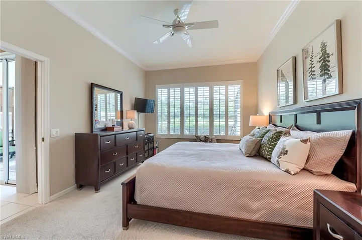 Bedroom featuring light colored carpet, crown molding, a ceiling fan, and baseboards
