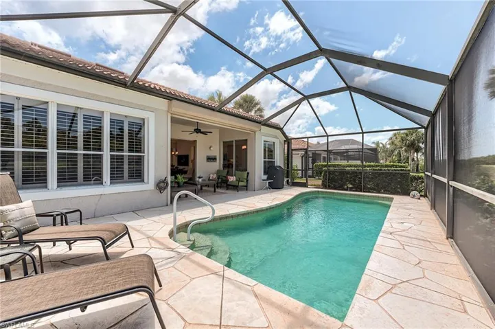 Swimming pool featuring a patio, ceiling fan, and glass enclosure