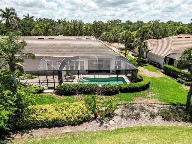 Rear view of house with a lanai, a tiled roof, a lawn, an outdoor pool, and a patio area