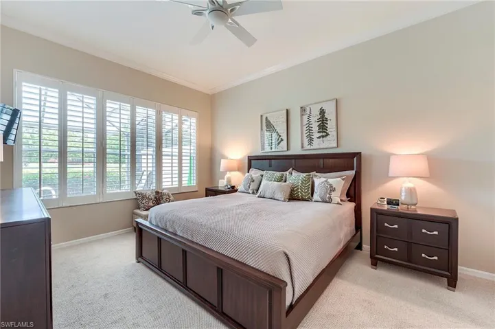 Bedroom featuring light colored carpet, ornamental molding, baseboards, and a ceiling fan