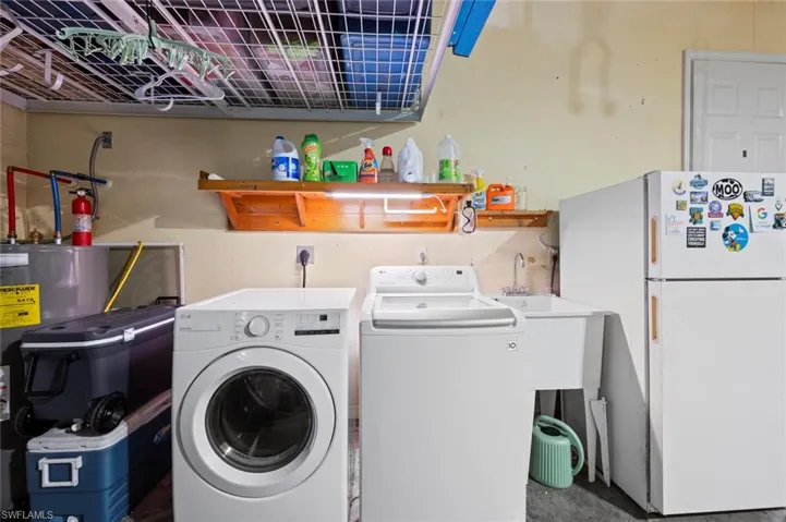Laundry area featuring independent washer and dryer, water heater, and concrete flooring