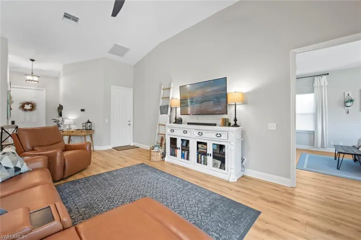 Living area with light wood-style flooring, lofted ceiling, and ceiling fan