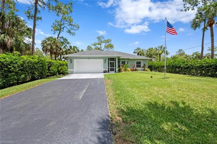 Ranch-style house with driveway, a garage, a front lawn, and stucco siding