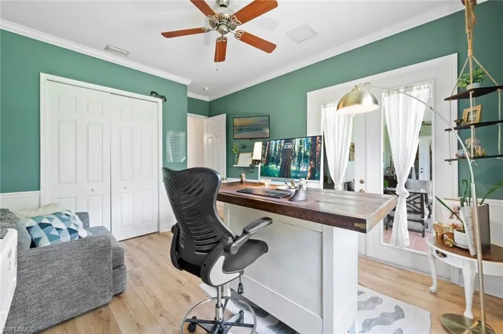 Home office with light wood-style flooring, ornamental molding, ceiling fan, and french doors