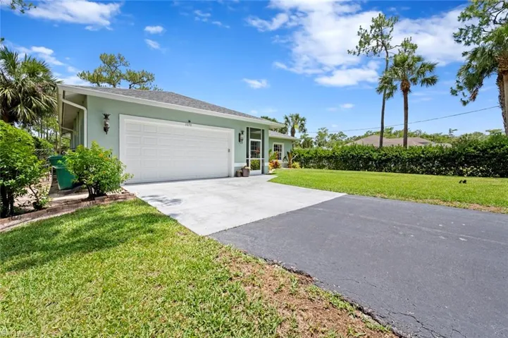 Ranch-style house with stucco siding, a front lawn, a garage, and driveway