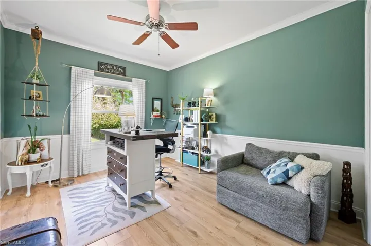 Home office featuring ornamental molding, wood finished floors, and a wainscoted wall