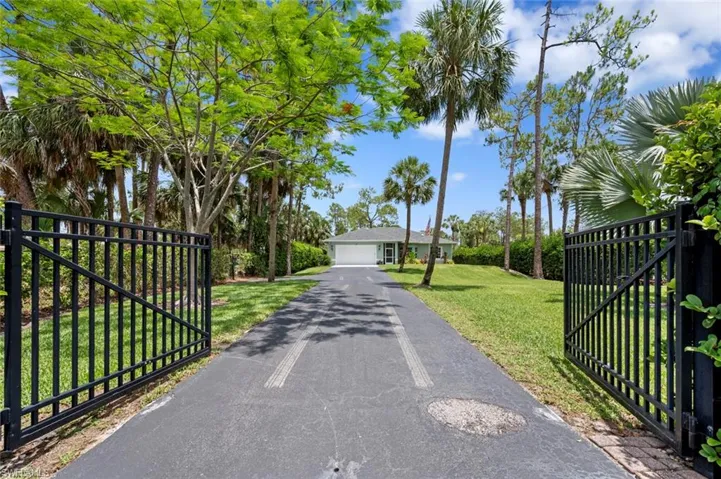 View of asphalt driveway featuring a gated entry and a gate