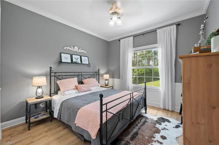 Bedroom featuring light wood-style flooring, ornamental molding, and a ceiling fan